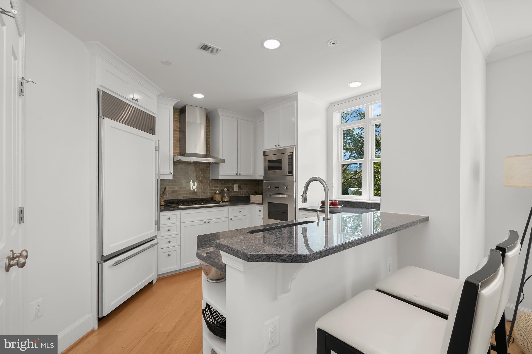 1414 22nd Street Northwest, Unit 41 Washington, DC 20037 - Photo 13 of 36 a kitchen with granite countertop stainless steel appliances a refrigerator a sink a stove a table and chairs