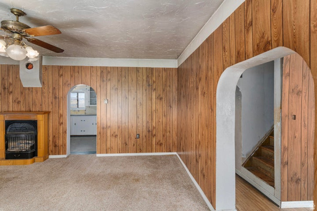 482 West 100 N Street Beaver, UT 84713 - Photo 4 of 41 Unfurnished living room featuring arched walkways, wooden walls, a ceiling fan, a fireplace, and carpet