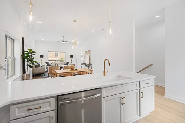 a kitchen with a sink dishwasher and white cabinets with wooden floor