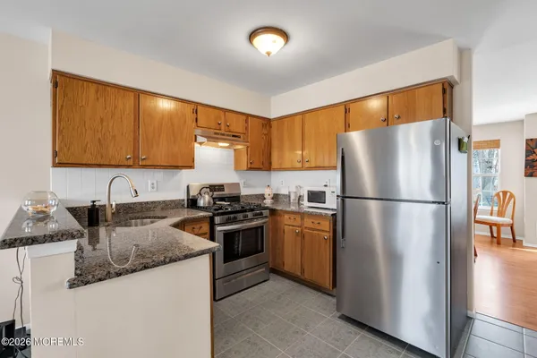 a kitchen with granite countertop stainless steel appliances a refrigerator a sink a stove a washer dryer and a refrigerator