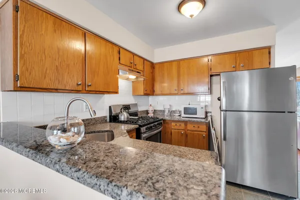 a kitchen with granite countertop a refrigerator stove and sink