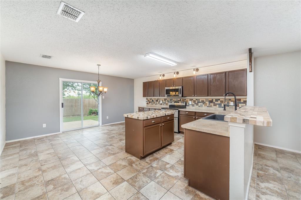 4408 Statesman Lane Fort Worth, TX 76244 - Photo 12 of 40 Kitchen featuring pendant lighting, sink, a textured ceiling, appliances with stainless steel finishes, and decorative backsplash