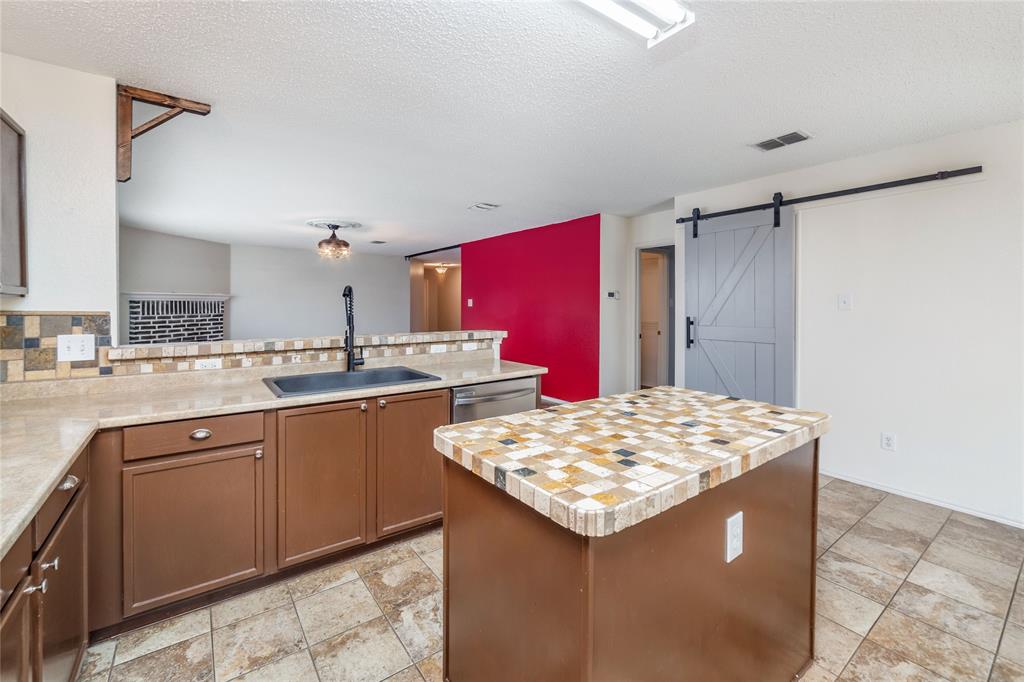 4408 Statesman Lane Fort Worth, TX 76244 - Photo 15 of 40 Kitchen with sink, stainless steel dishwasher, a kitchen island, backsplash, and a barn door