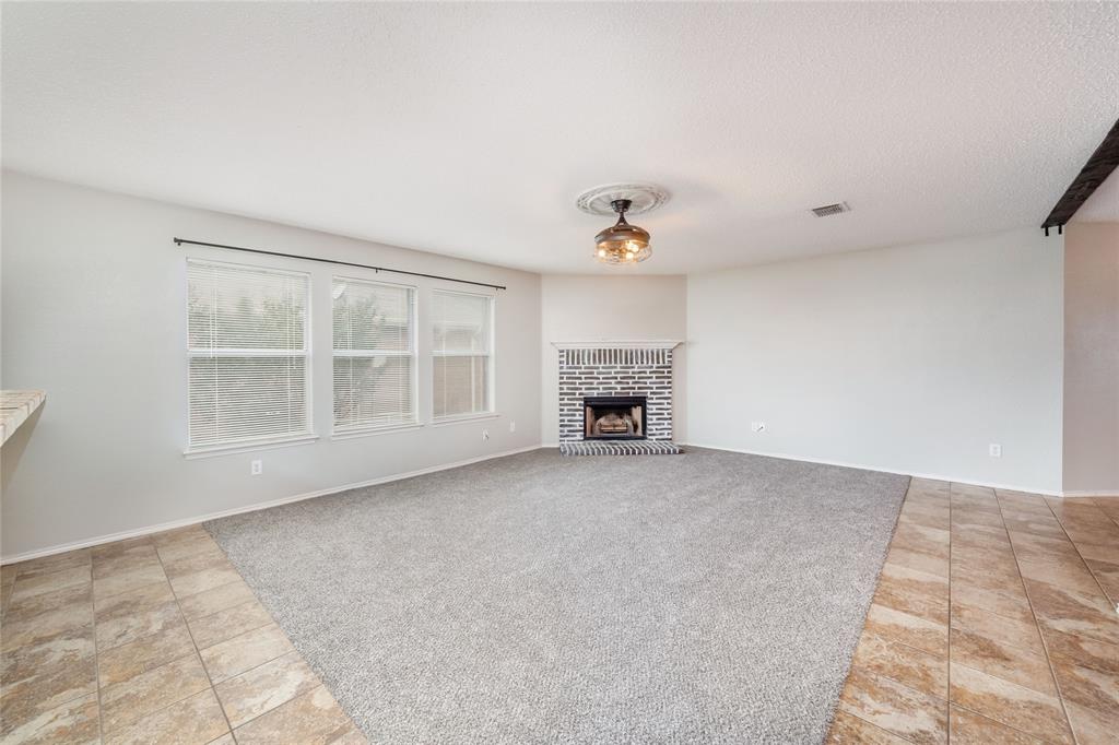 4408 Statesman Lane Fort Worth, TX 76244 - Photo 8 of 40 Unfurnished living room featuring a textured ceiling, a brick fireplace, and carpet flooring