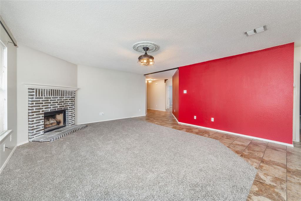 4408 Statesman Lane Fort Worth, TX 76244 - Photo 10 of 40 Unfurnished living room with a brick fireplace, carpet, and a textured ceiling