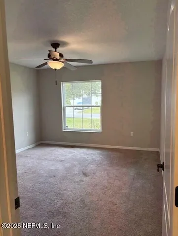 an empty room with windows and fan