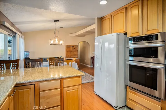 a kitchen with stainless steel appliances granite countertop a refrigerator a stove and a sink with cabinets