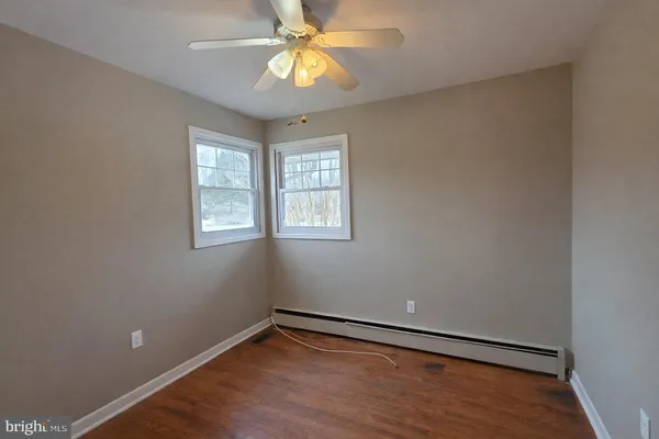 an empty room with wooden floor closet and chandelier fan