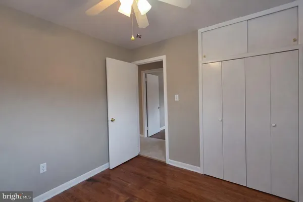 an empty room with wooden floor chandelier fan and windows