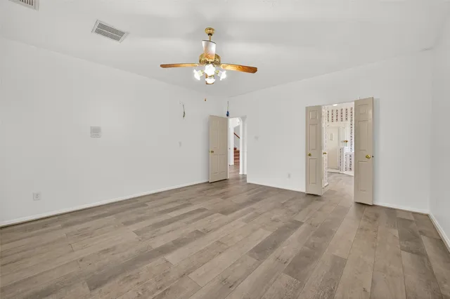 an empty room with wooden floor ceiling fan and window