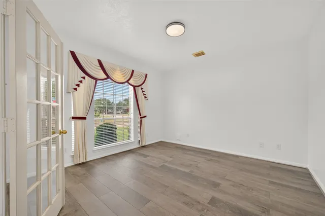 an empty room with wooden floor and windows