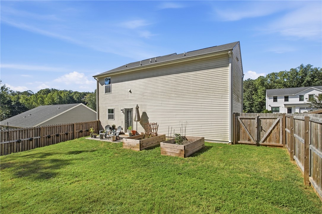 112 Wls Sta Road Seneca, SC 29678 - Photo 38 of 42 A wooden privacy fence surrounds the grassy backyard featuring raised garden beds and a small patio.