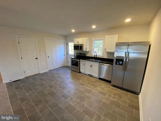 a kitchen with granite countertop a refrigerator and a stove top oven