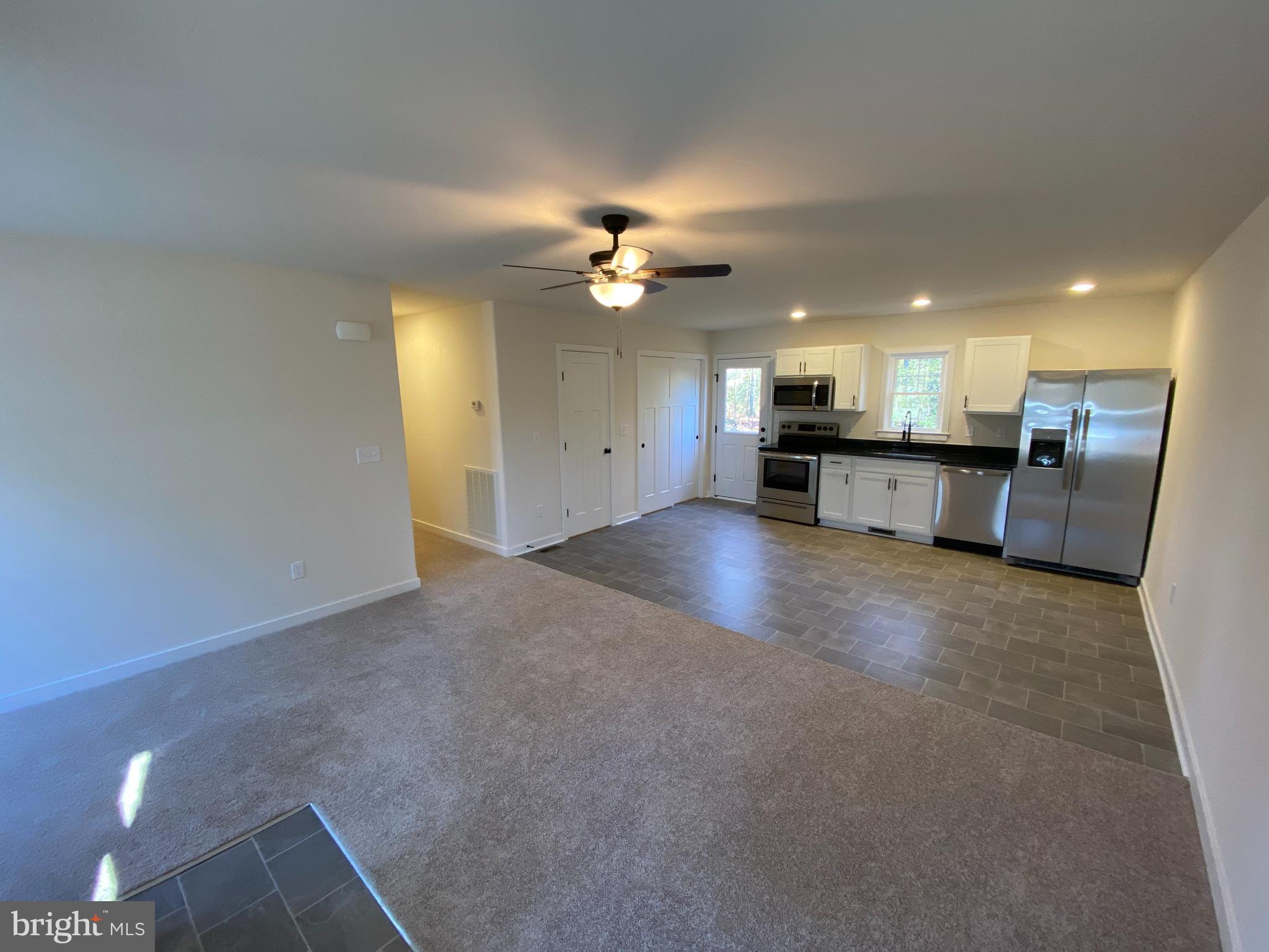 170 Forest Grove Road Colonial Beach, VA 22443 - Photo 9 of 34 a view of a kitchen with a sink a kitchen island white cabinets and a refrigerator