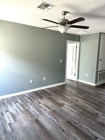 a view of a room with a ceiling fan and hardwood floor