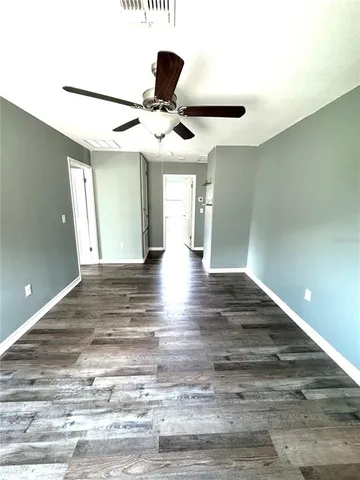 a view of an empty room with wooden floor and windows