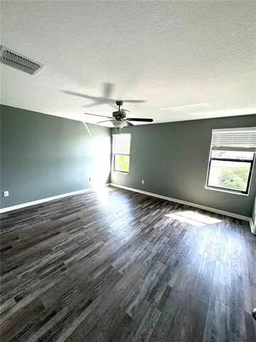 an empty room with wooden floor chandelier and windows