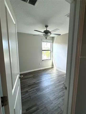 an empty room with wooden floor cabinet and windows