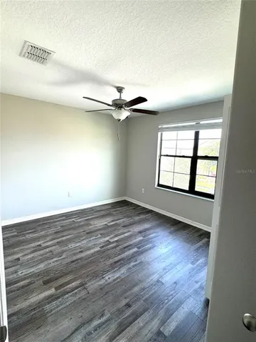 an empty room with wooden floor fan and windows