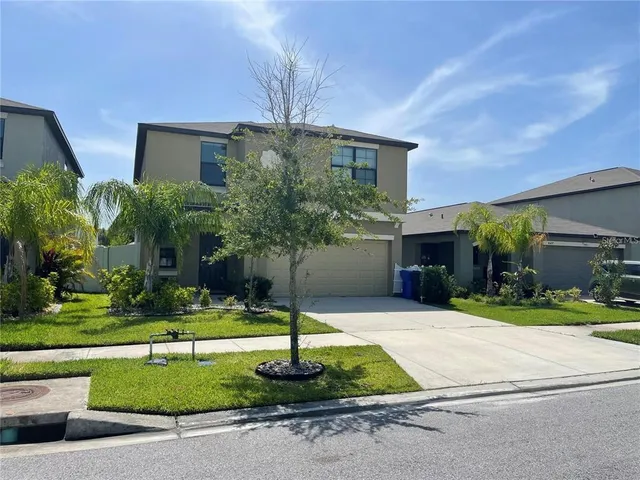 a front view of a house with a yard and potted plants