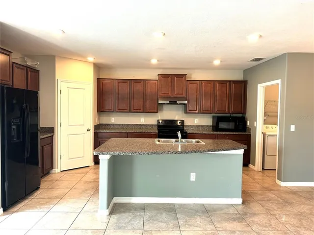 a view of a kitchen with stainless steel appliances granite countertop a refrigerator and a sink