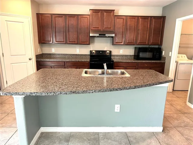 a kitchen with granite countertop a sink a stove and a microwave