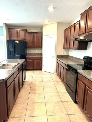 a kitchen with stainless steel appliances granite countertop a stove a sink and a refrigerator