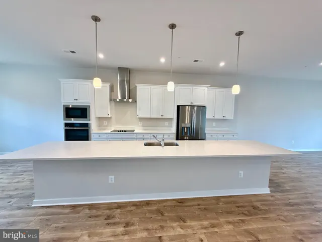 a large kitchen with stainless steel appliances a large counter top a stove and a chandelier