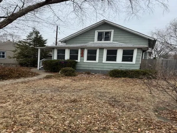 a front view of a house with yard and trees in the background