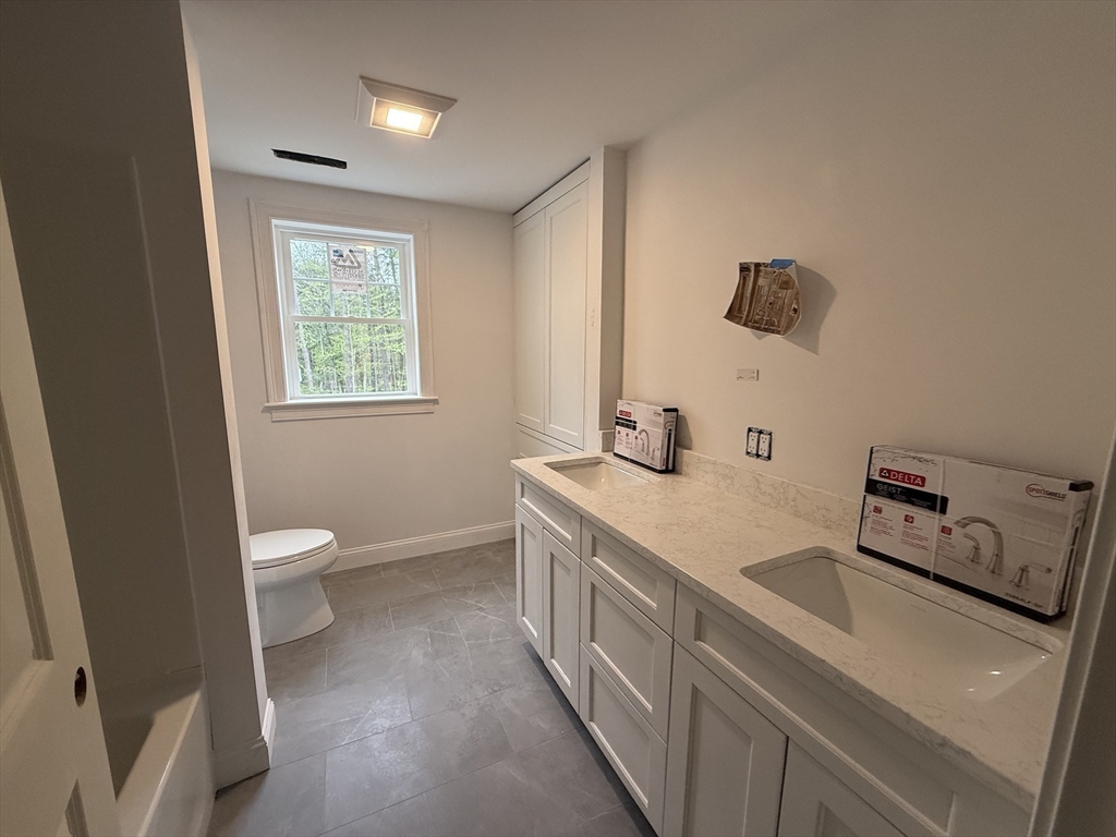 120 Maple Street Stow, MA 01775 - Photo 27 of 36 a bathroom with a double vanity sink a toilet and a window
