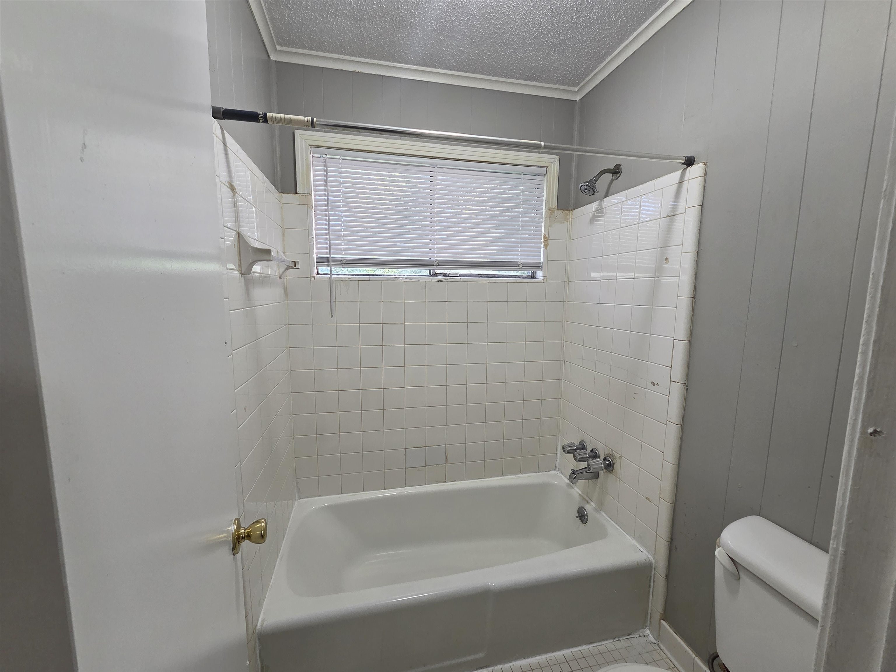 4573 Appleville Street Memphis, TN 38109 - Photo 17 of 22 Bathroom featuring crown molding, washtub / shower combination, a textured ceiling, and wood walls