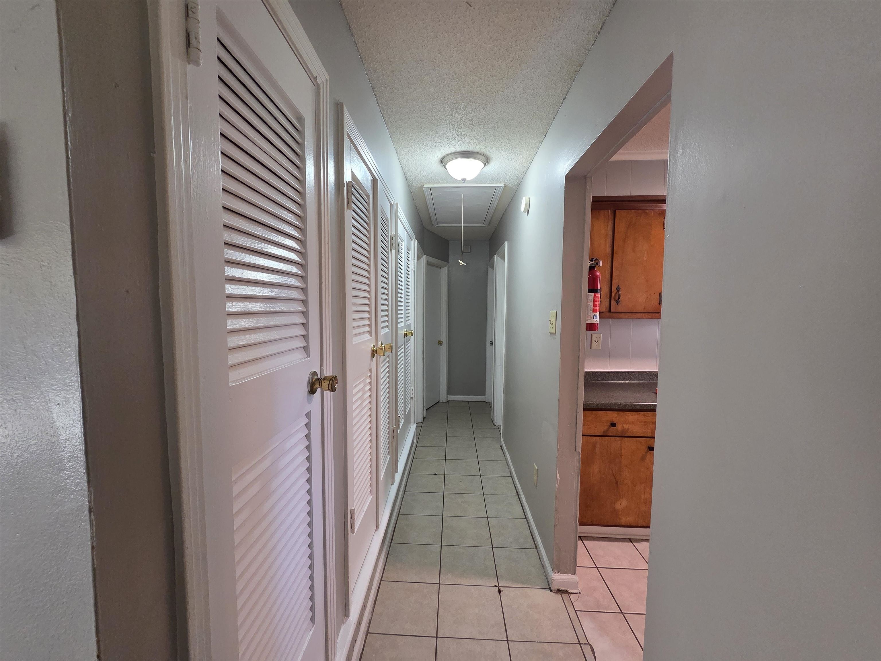4573 Appleville Street Memphis, TN 38109 - Photo 10 of 22 Hallway featuring attic access, light tile patterned floors, and a textured ceiling
