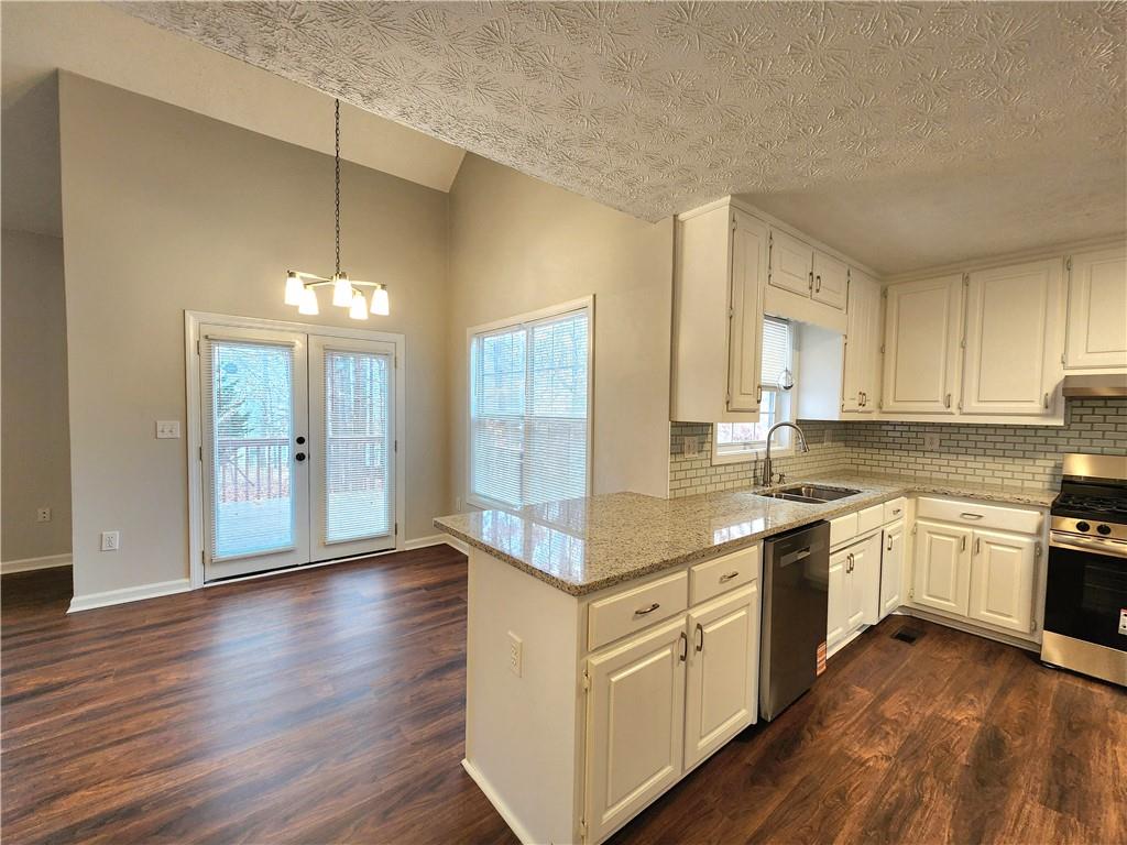 1645 Rushing River Way Suwanee, GA 30024 - Photo 11 of 38 a kitchen with stainless steel appliances granite countertop hardwood floor sink stove and wooden cabinets
