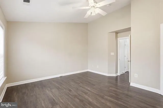 an empty room with wooden floor and fan