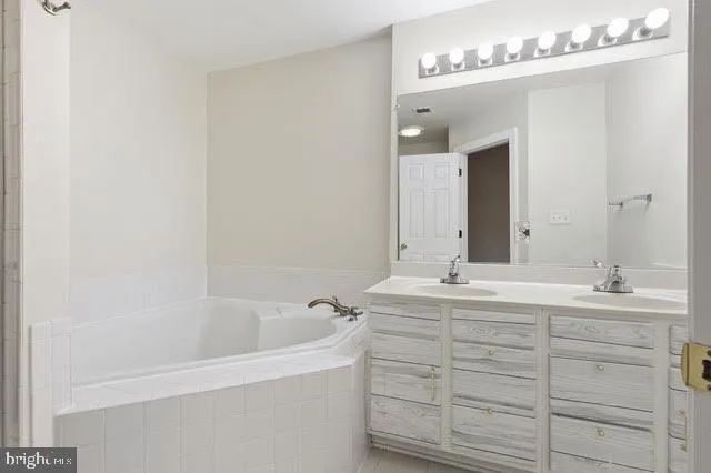 a bathroom with a double vanity sink mirror and bathtub