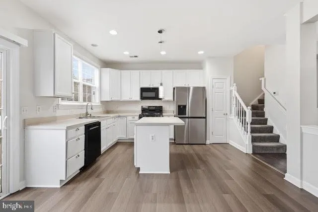 a kitchen with a sink a counter top space stainless steel appliances and cabinets