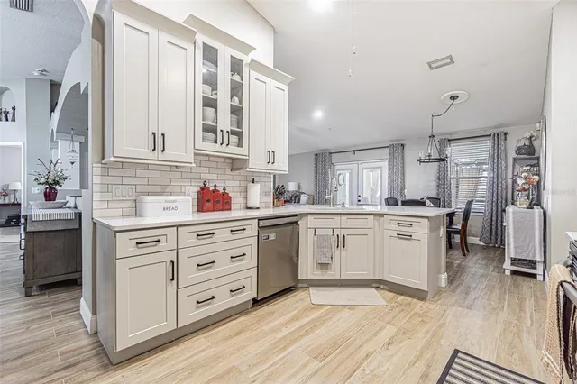 a kitchen with stainless steel appliances granite countertop a stove a sink and white cabinets with wooden floor