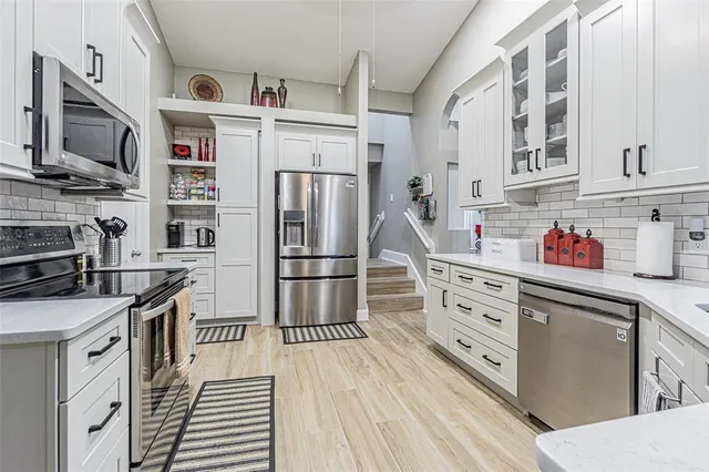 a view of a hallway with wooden floor and a bathroom