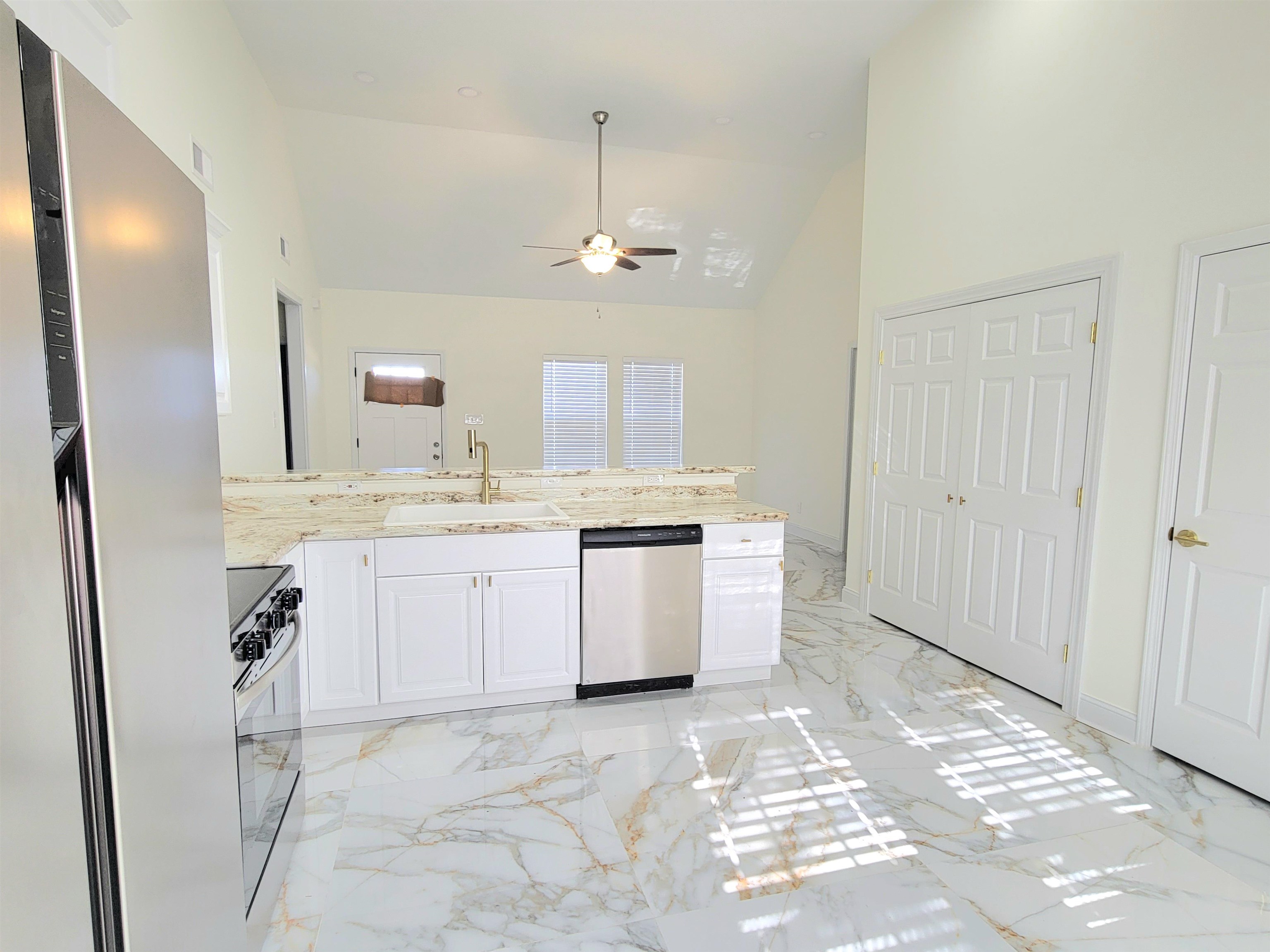 251 East Mitchell Road Memphis, TN 38109 - Photo 8 of 24 Kitchen with white cabinetry, sink, ceiling fan, high vaulted ceiling, and appliances with stainless steel finishes