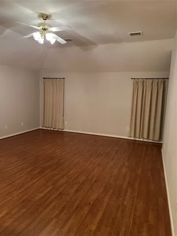 a view of room with hardwood floor and a ceiling fan