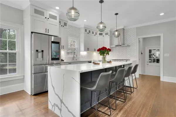 a kitchen with stainless steel appliances a dining table chairs and wooden floor