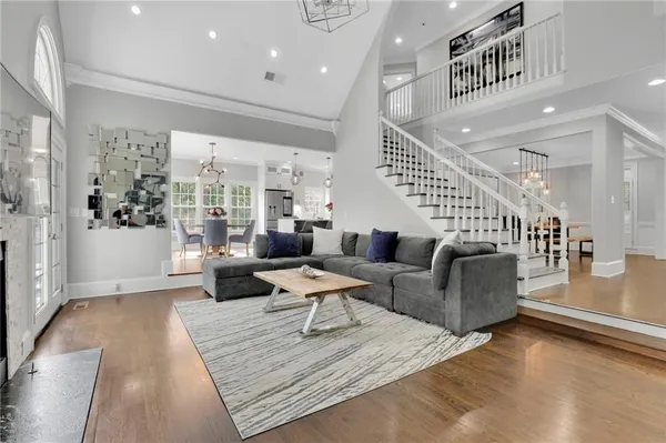 a living room with couches and kitchen view with wooden floor