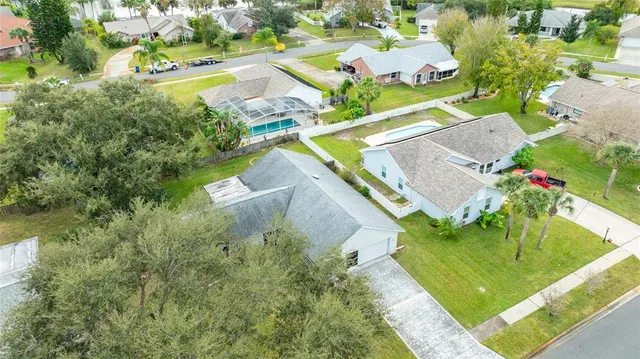 a view of a white house next to a yard and large tree