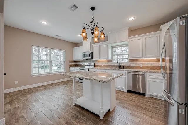 a kitchen with kitchen island granite countertop a sink cabinets and wooden floor