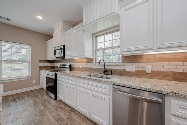 a kitchen with stainless steel appliances granite countertop a sink a stove cabinets and a window