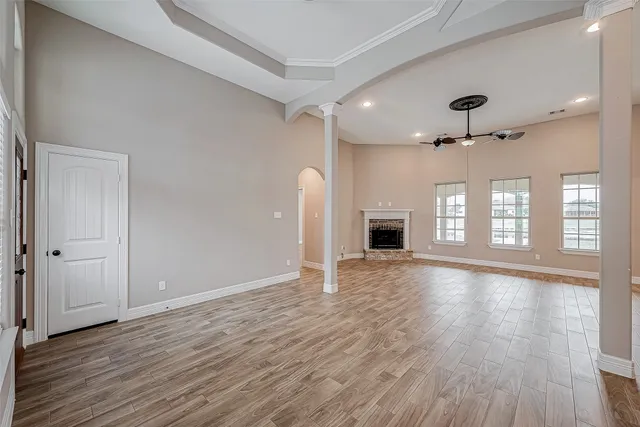 a view of an empty room with a window and wooden floor