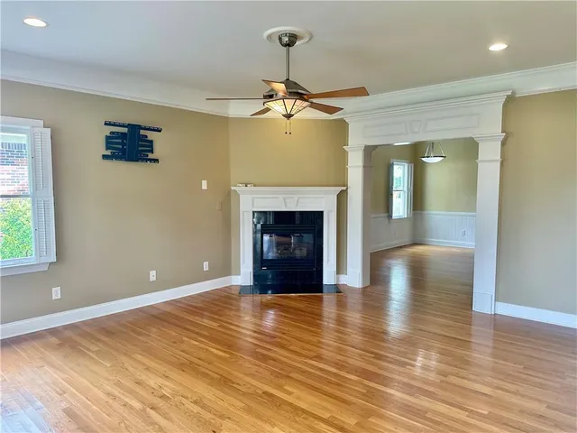 an empty room with wooden floor fireplace and windows