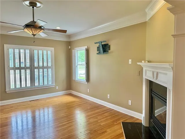 a view of an empty room with a window and wooden floor