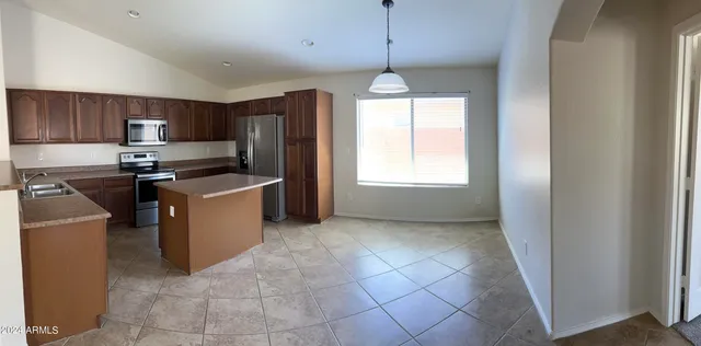 a kitchen with stainless steel appliances granite countertop a sink a stove a refrigerator cabinets and a window