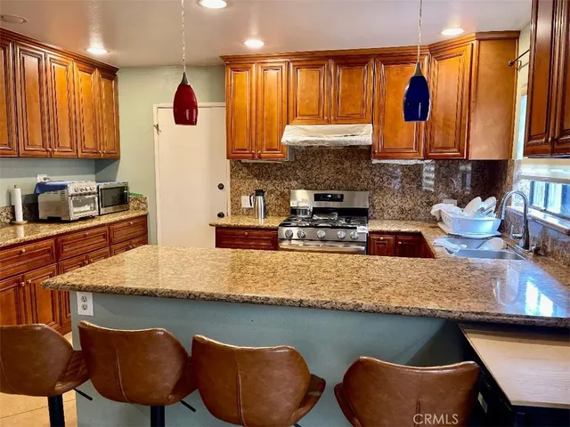 a kitchen with stainless steel appliances granite countertop a sink a stove window and cabinets